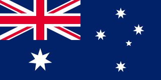 The flag of Australia has a dark blue field. It features the flag of the United Kingdom — the Union Jack — in the canton, beneath which is a large white seven-pointed star. A representation of the Southern Cross constellation, made up of one small five-pointed and four larger seven-pointed white stars, is situated on the fly side of the field.