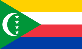 The flag of Comoros is composed of four equal horizontal bands of yellow, white, red and blue, with a green isosceles triangle superimposed on the hoist side of the field. This triangle has its base on the hoist end, spans about two-fifth the width of the field and bears a fly-side facing white crescent and four five-pointed white stars arranged in a vertical line along the opening of the crescent.