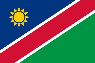 The flag of Namibia features a white-edged red diagonal band that extends from the lower hoist-side corner to the upper fly-side corner of the field. Above and beneath this band are a blue and green triangle respectively. A gold sun with twelve triangular rays is situated on the hoist side of the upper triangle.